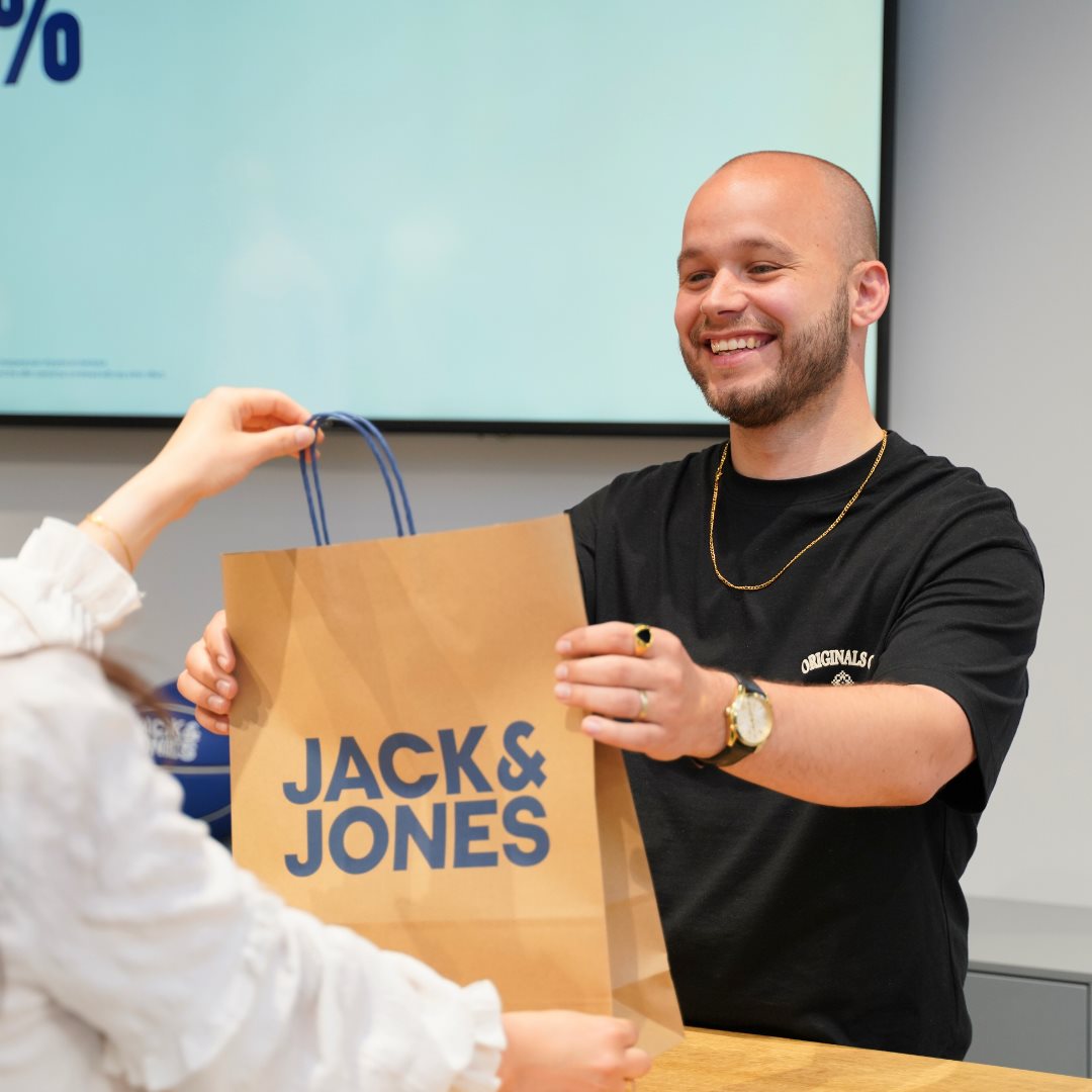 Medarbejder giver kunde en pose med tøj fra Jack & Jones i Randers.